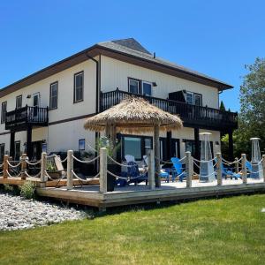 a house with a deck with chairs and an umbrella at Paradise Inn On the Beach in Port Elgin