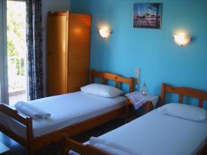 two beds in a room with blue walls at Magdalini in Votsi