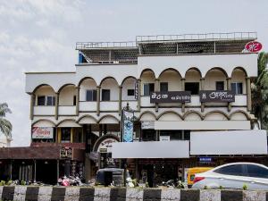 a large white building with cars parked in front of it at Aasra Lodge in Ratnagiri