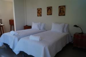 2 camas en una habitación con sábanas blancas y toallas en Indano Art Lodge, en Lamas
