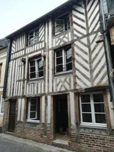 ein altes weißes Gebäude mit Fenstern auf einer Straße in der Unterkunft Duplex avec terrasse lumineux proche vieux bassin in Honfleur