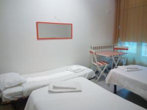 Zimmer mit 3 Betten, einem Tisch und einem Spiegel in der Unterkunft Hi Espinho - Pousada de Juventude in Espinho