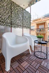 Casa M&J GuestHouse في أليكانتي: صف من الكراسي البيضاء وطاولة على الشرفة