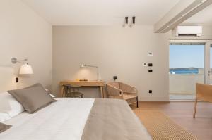 a bedroom with a bed and a desk and a window at MAIORA Luxury Island Suites in Sali