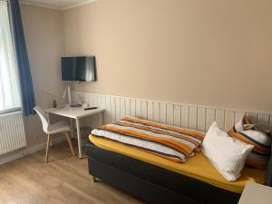 a bedroom with a bed and a table with a chair at Pension Triebischtal in Meißen