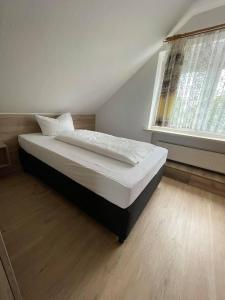 ein Bett in einem Schlafzimmer mit einem großen Fenster in der Unterkunft Pension am Meer in Norddeich