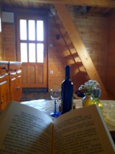 un libro abierto sobre una mesa con una botella y un vaso en Etno house Momcilo en Žabljak