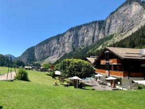a building in a field next to a mountain at Hameau des Prodains - Hôtel in Morzine +128 photos