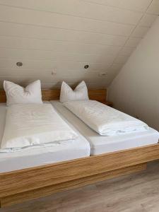 Cette chambre comprend 2 lits avec des draps et des oreillers blancs. dans l'établissement Pension am Meer, à Norddeich