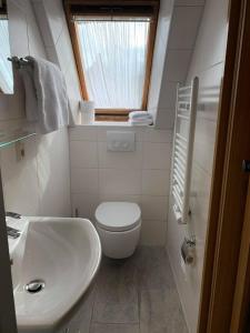 a white bathroom with a toilet and a sink at Pension am Meer in Norddeich