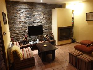 a living room with a tv and a stone wall at casaruraltiarosa in Quintanilla del Agua