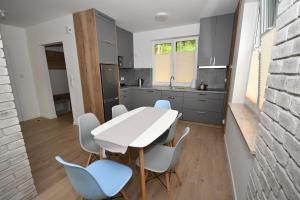 a kitchen with a white table and blue chairs at Dom w głębi lasu in Suwałki