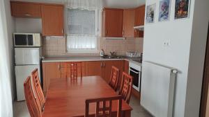 cocina con mesa de madera, sillas y nevera en Mona apartment, en Bükfürdő
