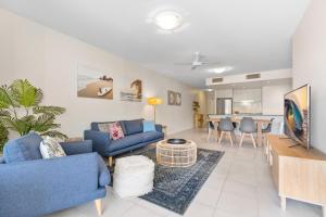 a living room with blue couches and a dining room at Drift Apartments - Tweed Coast Holidays ® in Kingscliff