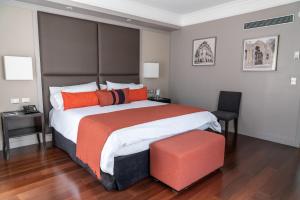 a bedroom with a large bed with orange pillows at Carles Hotel in Buenos Aires