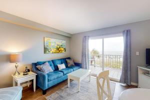 a living room with a blue couch and a balcony at Seacrest #202 in Gulf Shores