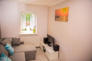 ein Wohnzimmer mit einer Couch und einem Fenster in der Unterkunft ENKLAWA NAD KWISĄ [APARTAMENT 1] in Świeradów-Zdrój