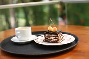 a piece of cake on a plate with a cup of coffee at Magnetiti Hotel in Ureki