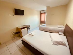 Habitación pequeña con 2 camas y TV. en Star Hotel en Taguatinga