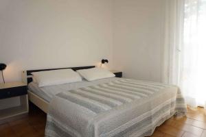 a white bedroom with a bed with two pillows at Holiday home Porto Santa Margherita 40286 in Porto Santa Margherita di Caorle