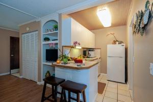 eine Küche mit einem weißen Kühlschrank und 2 Barhockern in der Unterkunft Sandpiper 120B in Princeville