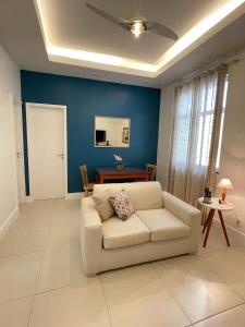 a living room with a white couch and a blue wall at Point de Ipanema - 2 quartos in Rio de Janeiro