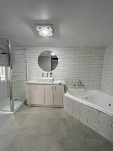 a bathroom with a tub and a sink and a mirror at Central Executive Spa Apartment in Ballarat