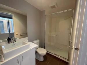 a bathroom with a shower and a toilet and a sink at Central Executive Spa Apartment in Ballarat