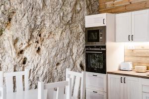 a kitchen with white cabinets and a stone wall at sziklavendeghaz in Veszprém