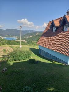 uma casa com um telhado vermelho num campo verde em Vila Suza em Jezdići