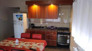 a kitchen with wooden cabinets and a table with red chairs at Departamento Cerro Negro in Villa General Belgrano