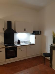 a kitchen with white cabinets and a stove top oven at Appartement Picasso centre historique Perpignan in Perpignan