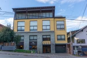 Un edificio amarillo con ventanas a una calle. en Belgrano Decks, en San Carlos de Bariloche