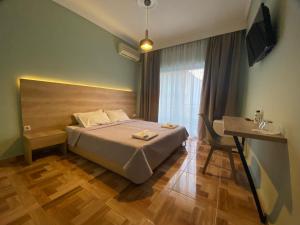 een slaapkamer met een bed, een bureau en een televisie bij Moudania Mare Hotel in Nea Moudania