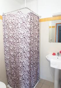 a bathroom with a toilet, sink, and shower curtain at Hotel Oasis de Kiamu in Lifou