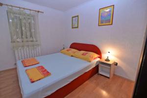 a small bedroom with a bed and a table with a lamp at Apartments in Veli Losinj 33612 in Veli Lošinj