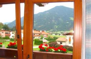 a window with red flowers and a view of a mountain at Apartments in Kaltenbach/Zillertal 751 in Kaltenbach