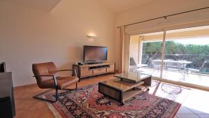 Il comprend un salon avec une chaise et une télévision à écran plat. dans l'établissement Sainte-Maxime - 3 bedroom apartment, air conditioned, outdoor terrace, swimming pool, à Sainte-Maxime