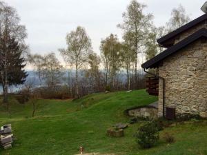 a stone building on a grassy hill next to a house at Holiday home in Madonna Del Sasso 22866 in Madonna del Sasso