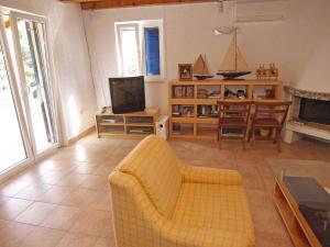 a living room with a yellow couch and a television at Holiday home in Veli Losinj 36387 in Veli Lošinj