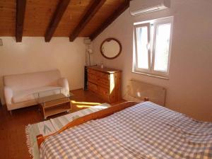 a bedroom with a bed and a window and a couch at Holiday home in Veli Losinj 36387 in Veli Lošinj