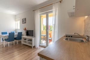 a kitchen with a sink and a table with blue chairs at Apartmani Cres in Cres