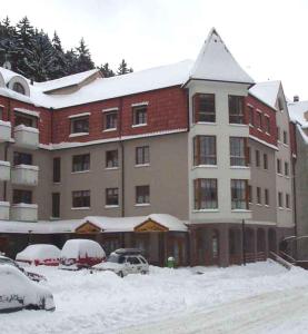 un edificio cubierto de nieve con coches aparcados en un aparcamiento en Apartments in Jachymov/Erzgebirge 33569, en Jáchymov