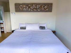 um quarto com uma cama grande e lençóis brancos em The Rooms at Woody Point em Bonne Bay