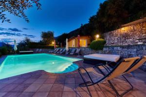 a swimming pool with chairs and a table and a stone wall at Apartments in Malcesine/Gardasee 22016 in Assenza di Brenzone