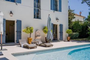 a patio with chairs and an umbrella next to a pool at SERRENDY Villa in Cap dAntibes near beaches in Antibes