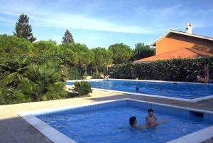 Holiday home in Lignano 21664 في لينانو سابيادورو: شخصين يسبحون في مسبح