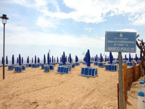 a beach with blue chairs and umbrellas and a sign at Apartments Porto Santa Margherita 25671 in Porto Santa Margherita di Caorle
