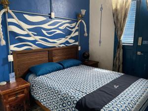 1 dormitorio con 1 cama con pared azul en Chuchumbé Hotel & Hostal, en Veracruz