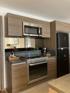 een keuken met een roestvrijstalen fornuis en een magnetron bij Yellow & Blue Apartment HP - Sur in Mexico-Stad